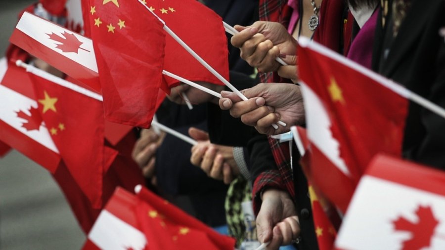 People gather at the airport holding Chinese and Canadian flags while waiting for the arrival of Chinese President Hu Jintao in Vancouver, British Columbia, September 16, 2005. Hu is on the west coast of Canada for a two-day visit. REUTERS/Andy Clark AC/YH