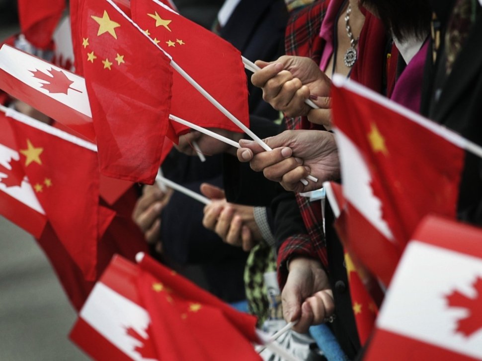People gather at the airport holding Chinese and Canadian flags while waiting for the arrival of Chinese President Hu Jintao in Vancouver, British Columbia, September 16, 2005. Hu is on the west coast of Canada for a two-day visit. REUTERS/Andy Clark AC/YH