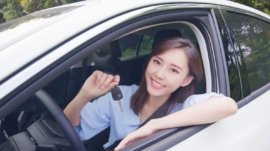 pretty woman sit in the car with key and smile happy