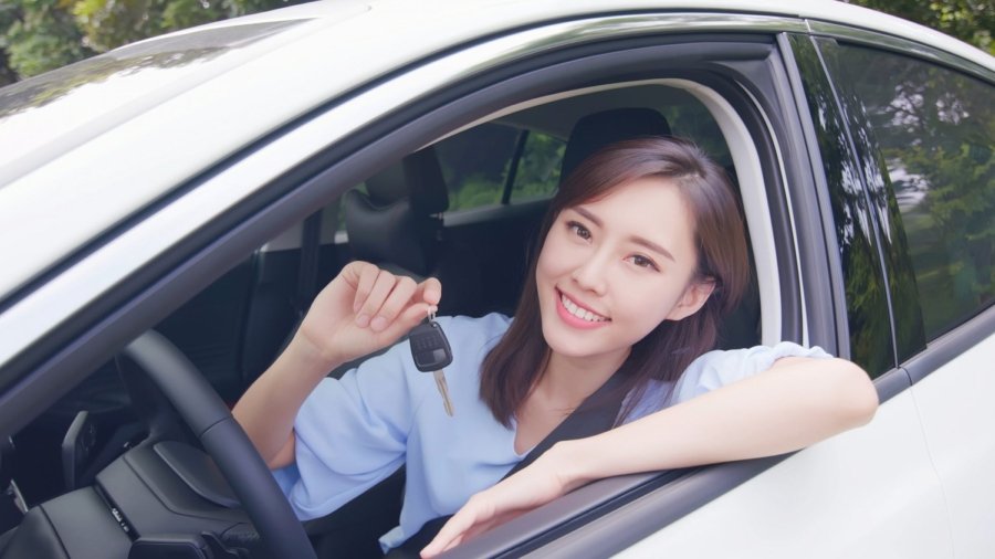 pretty woman sit in the car with key and smile happy
