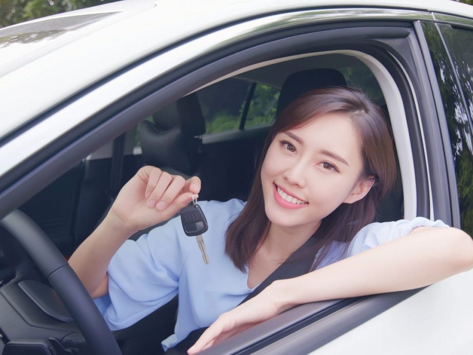 pretty woman sit in the car with key and smile happy