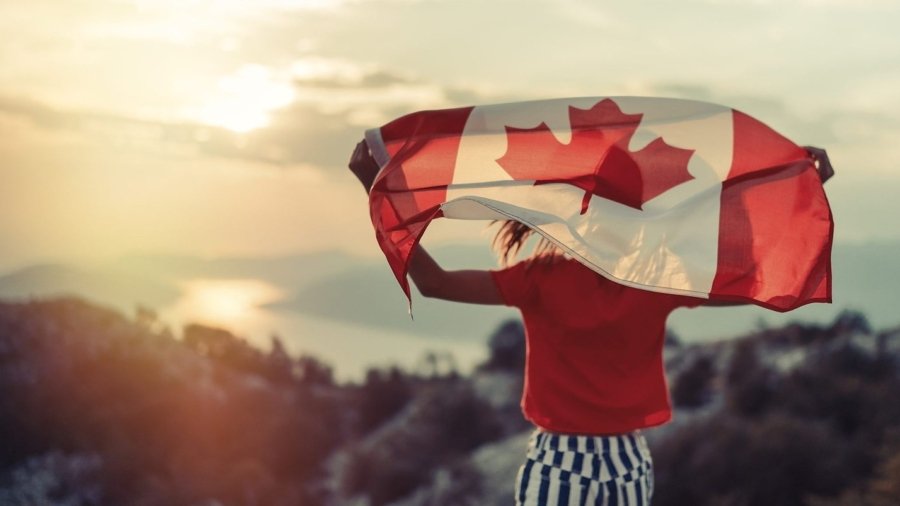 Happy child teenage girl waving the flag of Canada while running at sunset