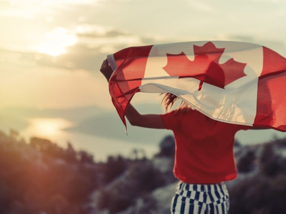 Happy child teenage girl waving the flag of Canada while running at sunset